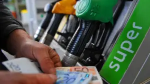 Pompa di benzina con due mani che mostrano soldi per rappresentare gli extraprofitti delle società energetiche