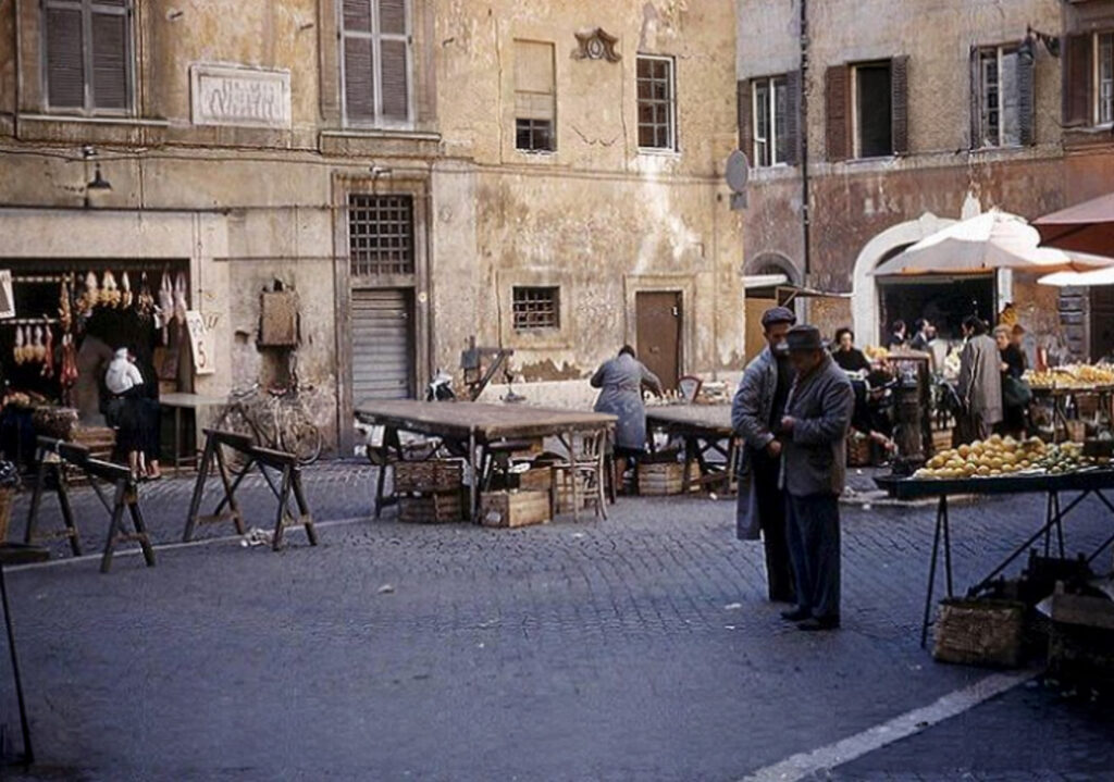 Foto storica di piazza delle Coppelle con i banchi del mercato e le botteghe affacciate sulla piazza a Roma