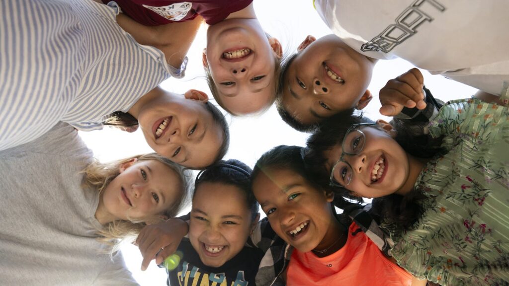 Gruppo di bambini sorridenti fotografati in cerchio per un articolo sulla povertà infantile in Italia